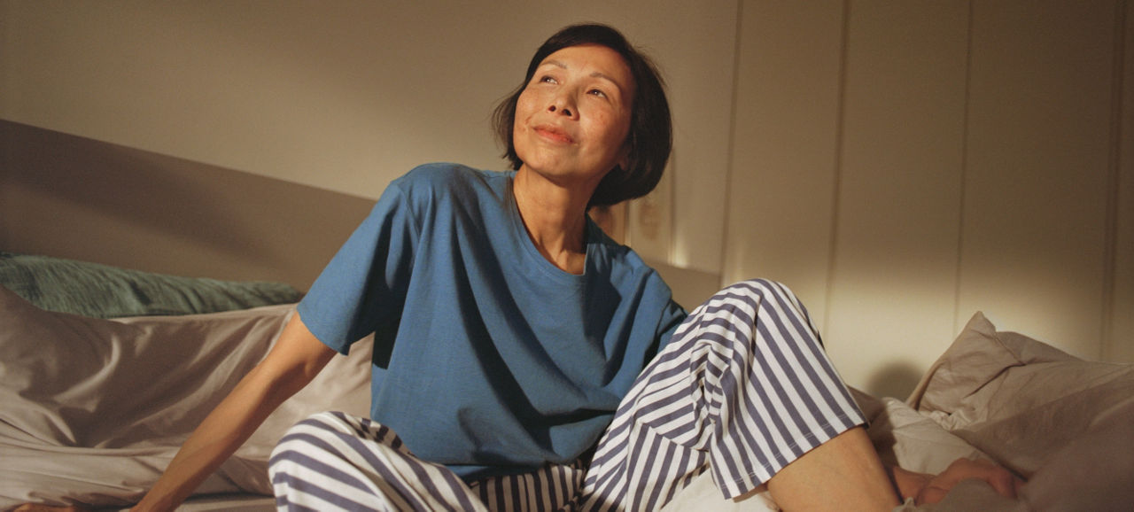 Woman in bed looking up and smiling