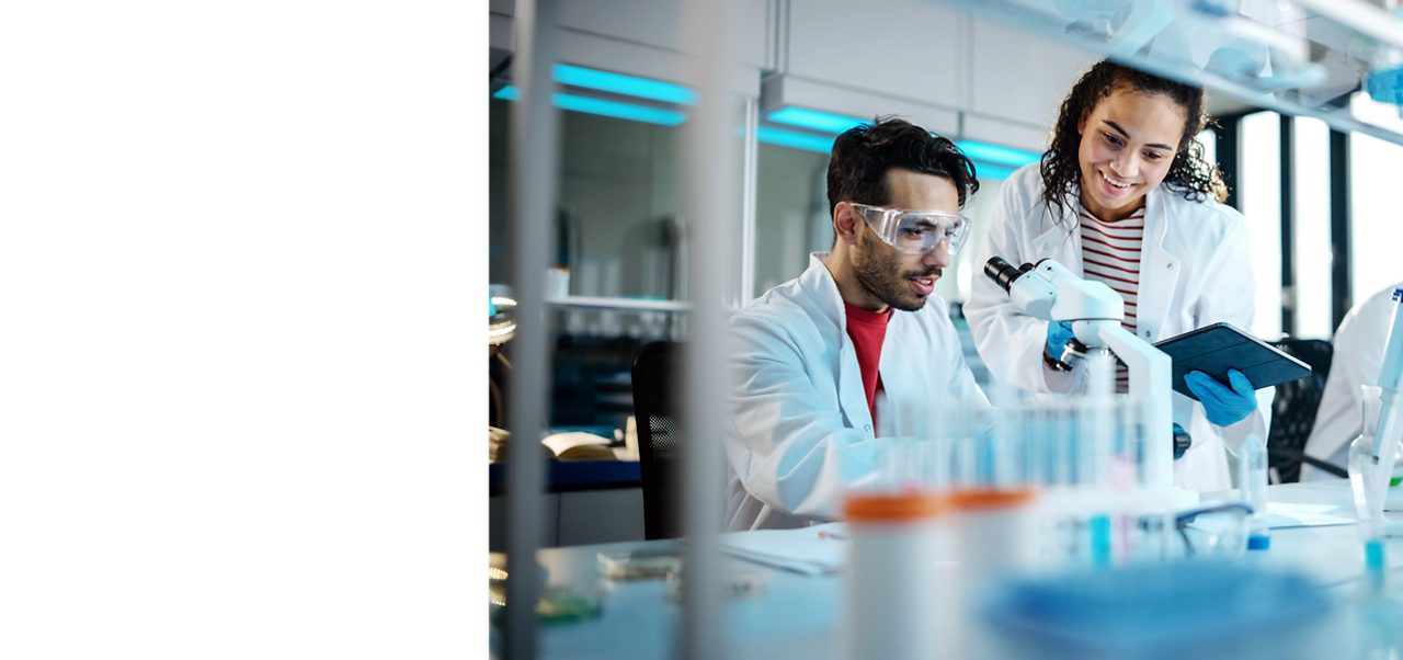 Astellas scientists examine samples under a microscope, reflecting the company’s research-driven mission.