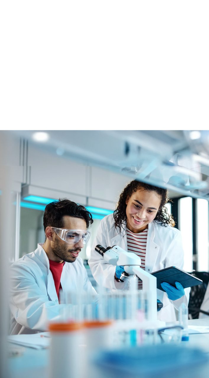 Astellas scientists examine samples under a microscope, reflecting the company’s research-driven mission.