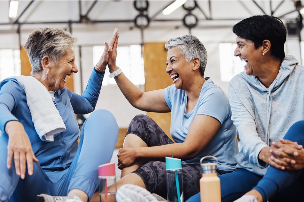 Gymnase, high five et groupe de femmes mûres célébrant après un cours de fitness, conversation et félicitations sur le sol. Exercice, création de liens et femme âgée heureuse avec des amis assis ensemble pendant l'entraînement