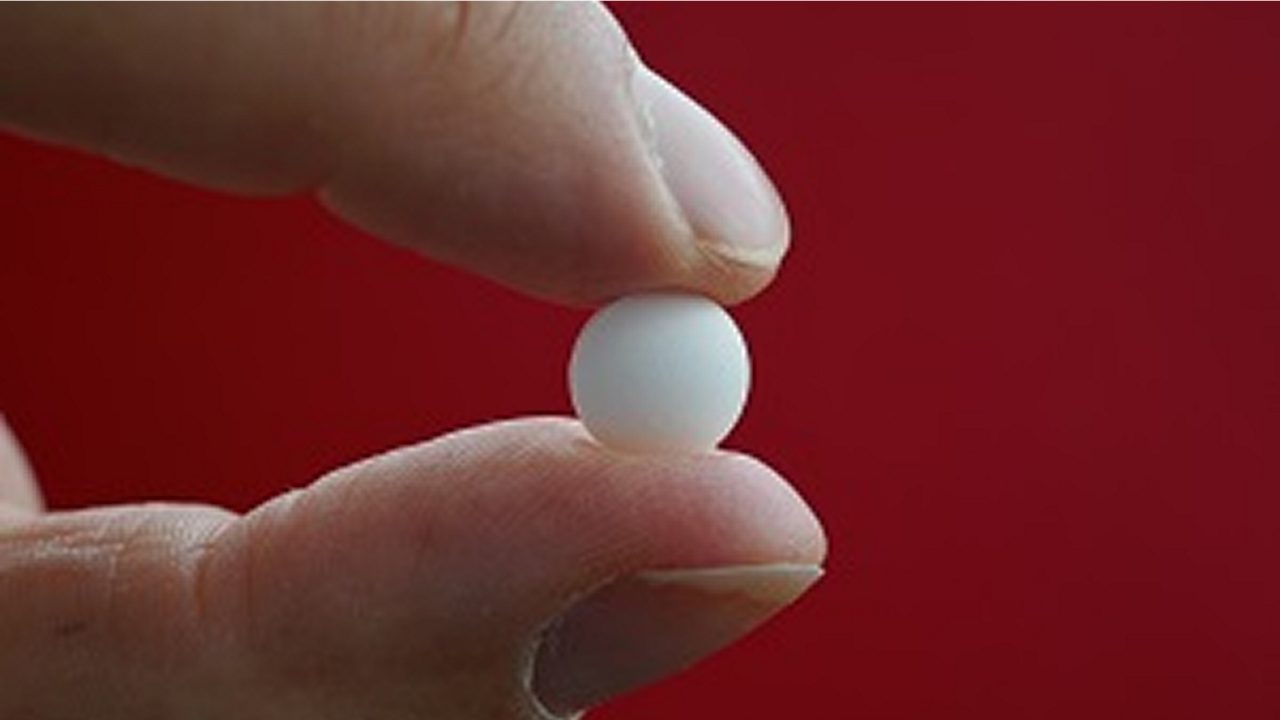 A healthcare professional holds a pill, indicating a new pediatric formulation.