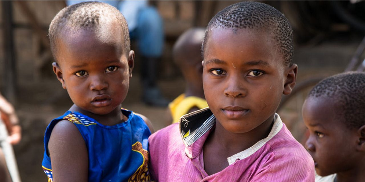 A young boy holds his sibling, showing Astellas’ focus on pediatric treatment options for schistosomiasis.