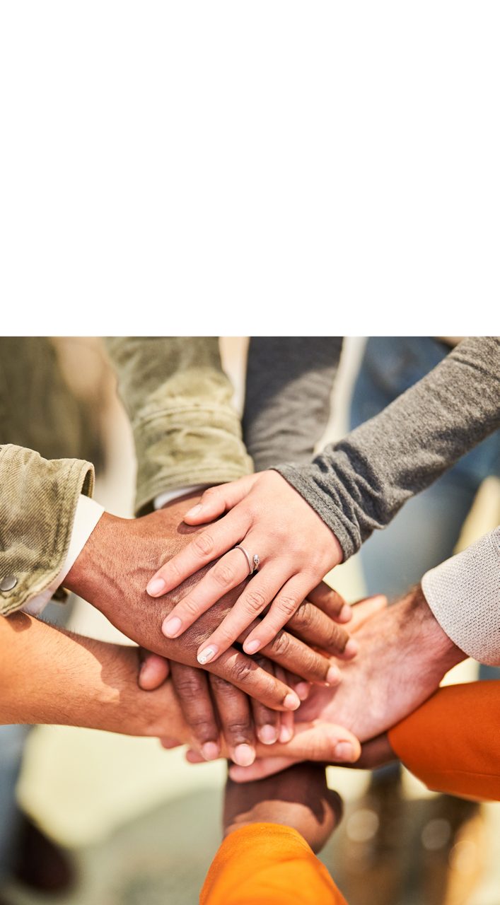 A team puts their hands in a huddle, showing Astellas’ focus on building a sustainable society.