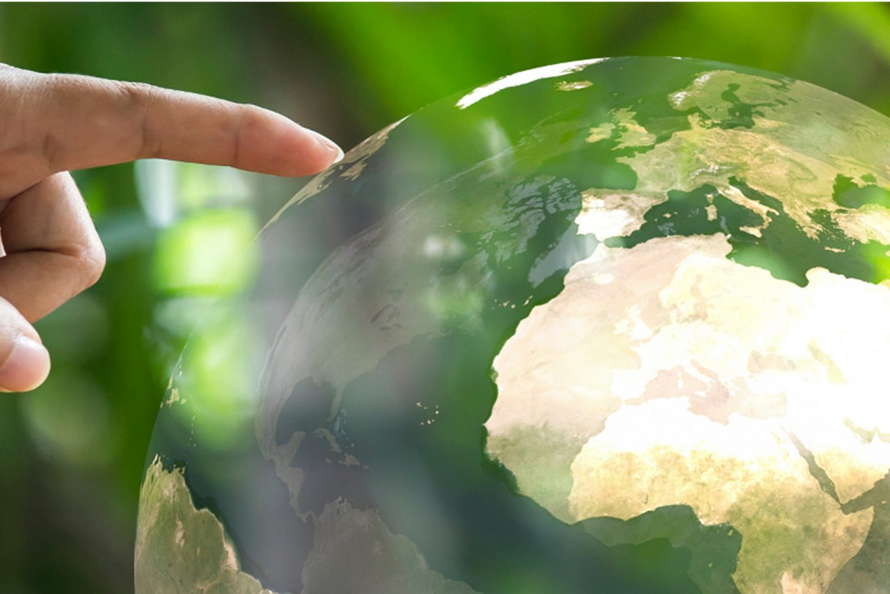 A hand touches a globe, showing how Astellas promotes activities to prevent global environmental pollution.