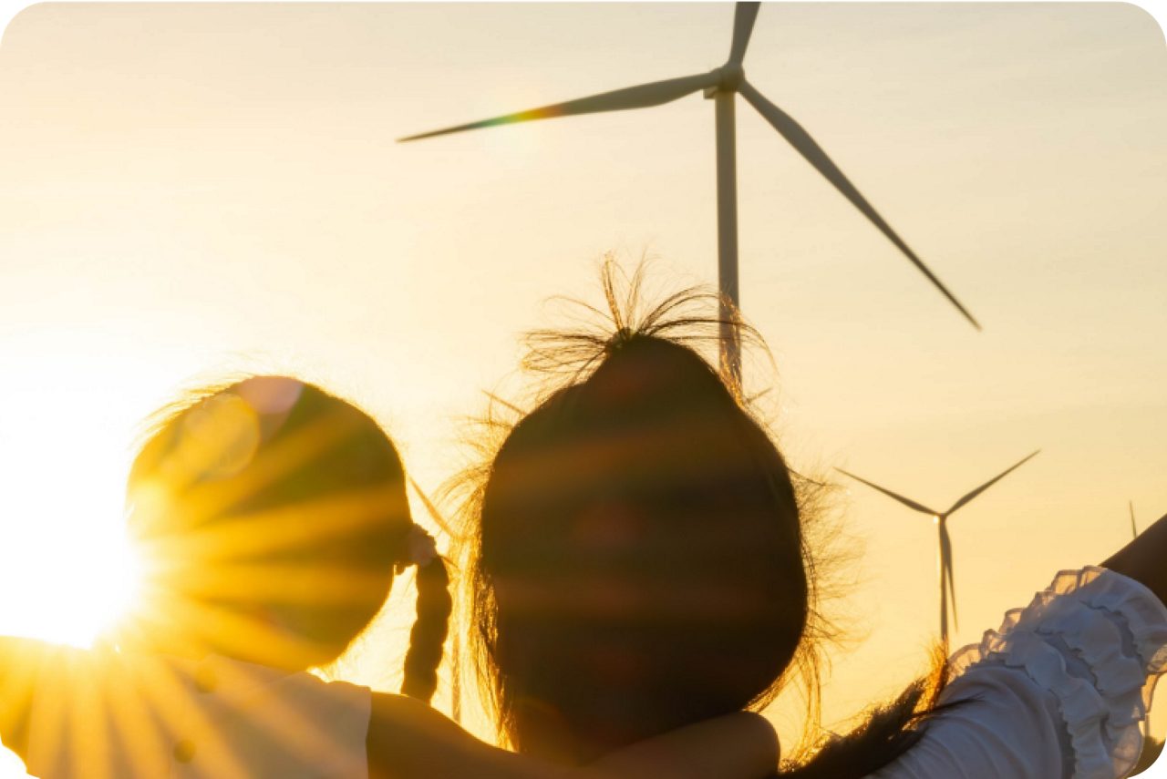Children look at a wind turbine, illustrating Astellas’ goal to reduce its energy consumption.