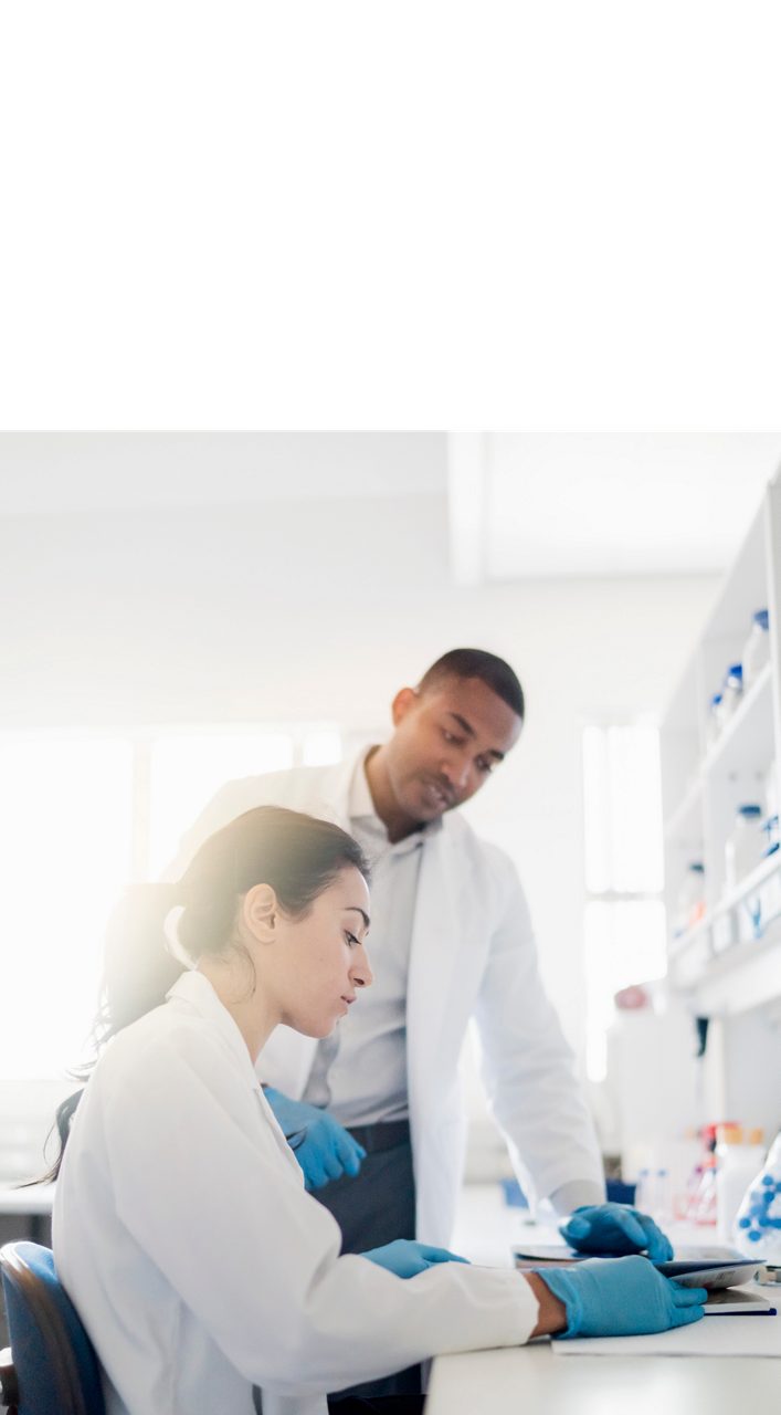 Astellas scientists examine samples under a microscope, reflecting the company’s research-driven mission.