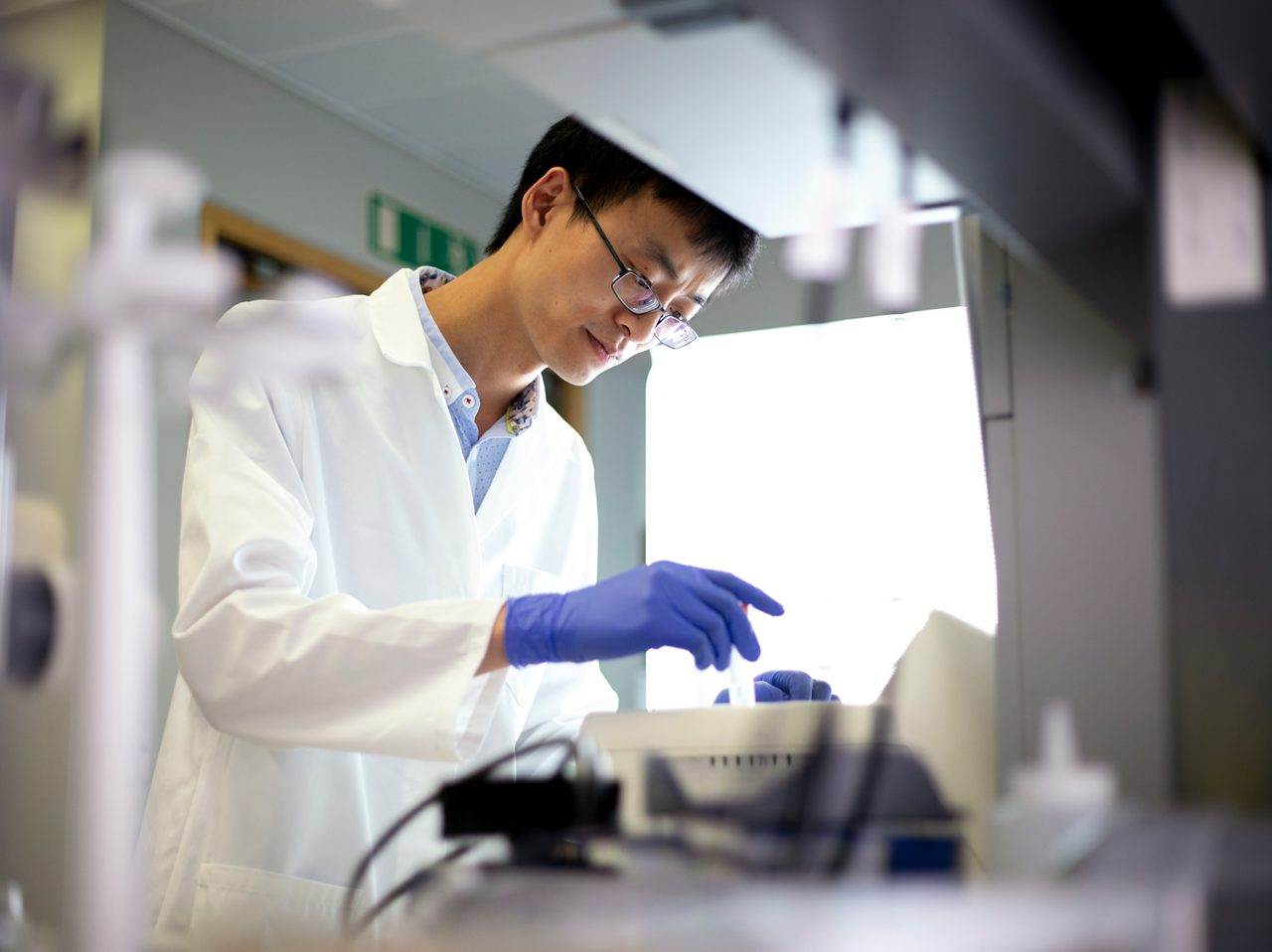 An Astellas scientist examines samples under a microscope, reflecting the company’s focus on taking science in new directions. 