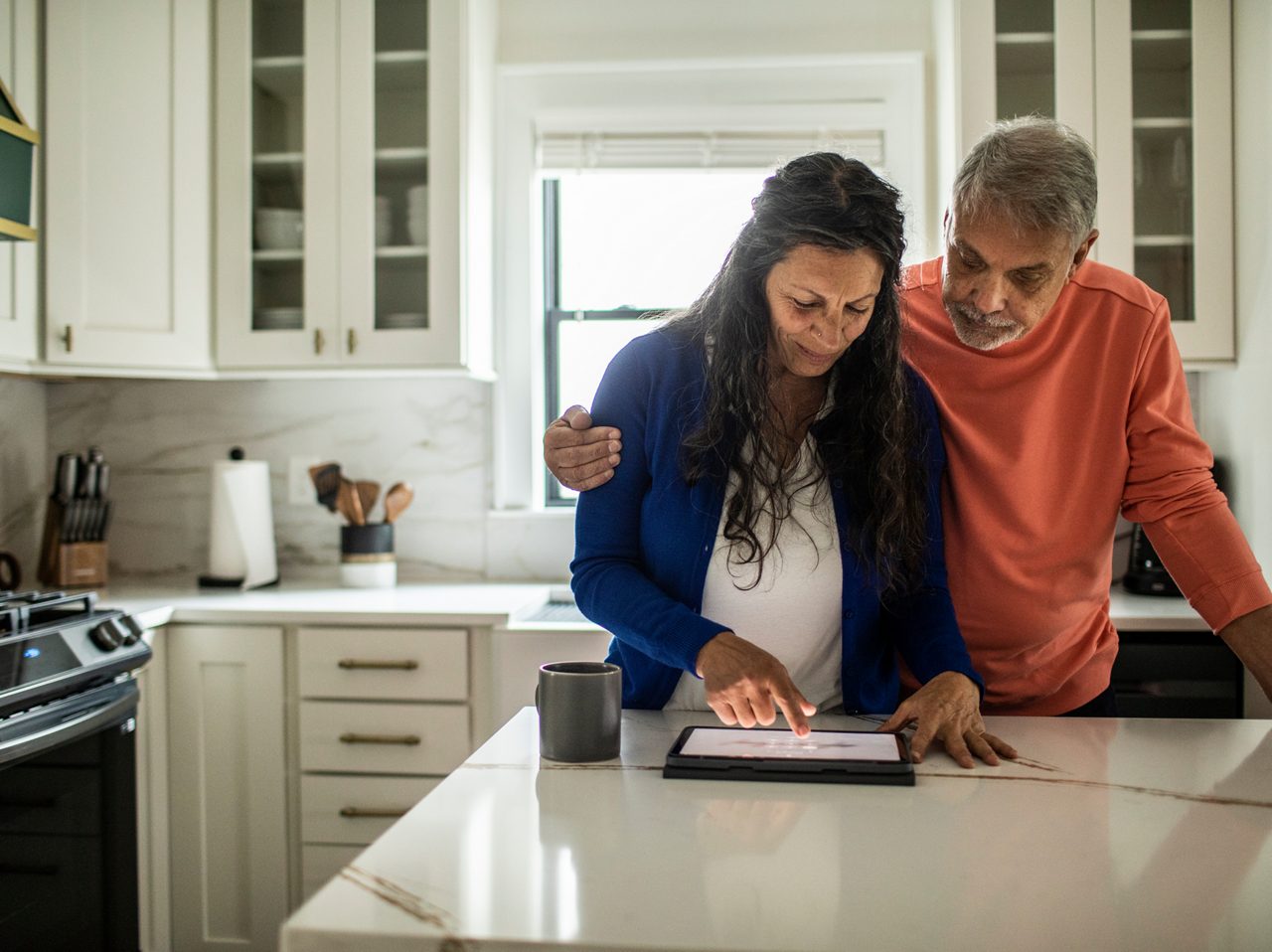 A couple huddles around a mobile device, illustrating how Astellas is using digital health technologies to provide care to patients.