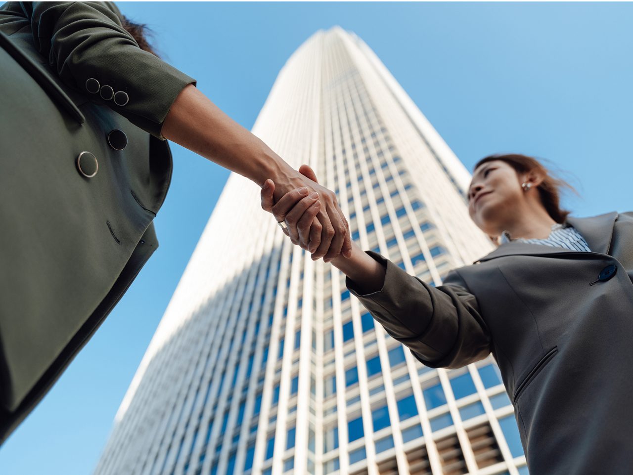 Two Astellas employees shake hands, symbolizing the company’s goal to maximize its return to shareholders.