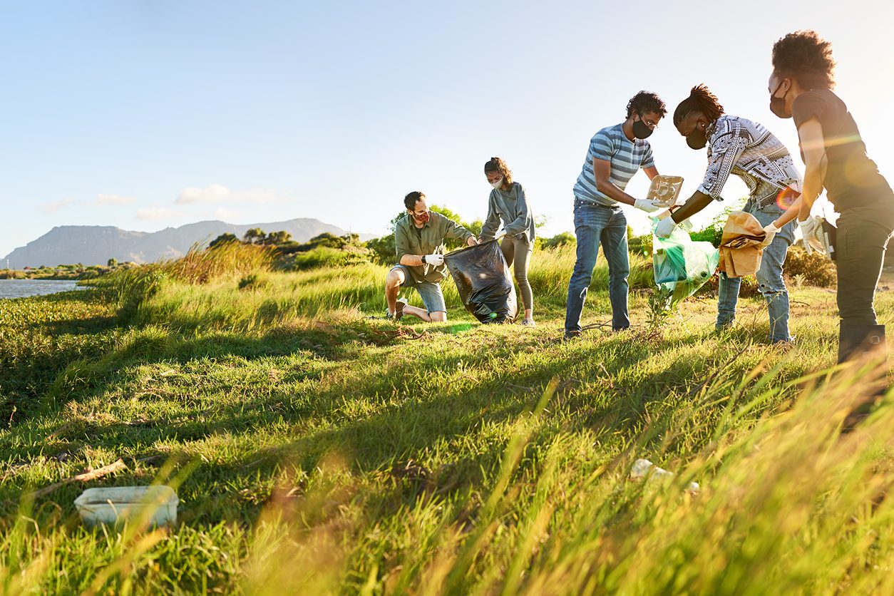 Astellas employees volunteering to clean a field, promoting sustainability and community engagement.