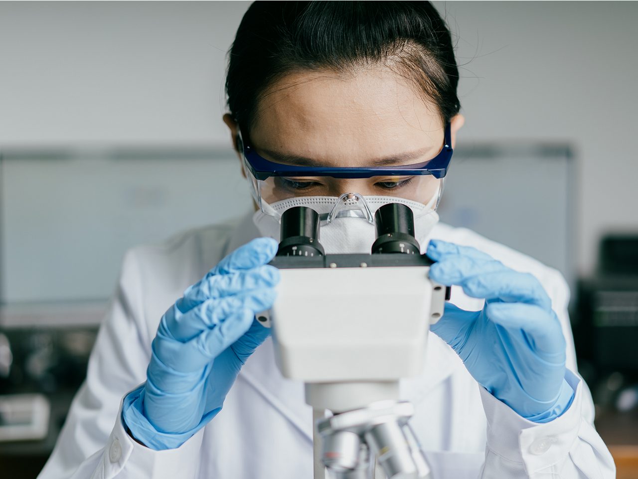 A scientist studies samples under a microscope, advancing Astellas' strategies to reduce the impact of VMS.