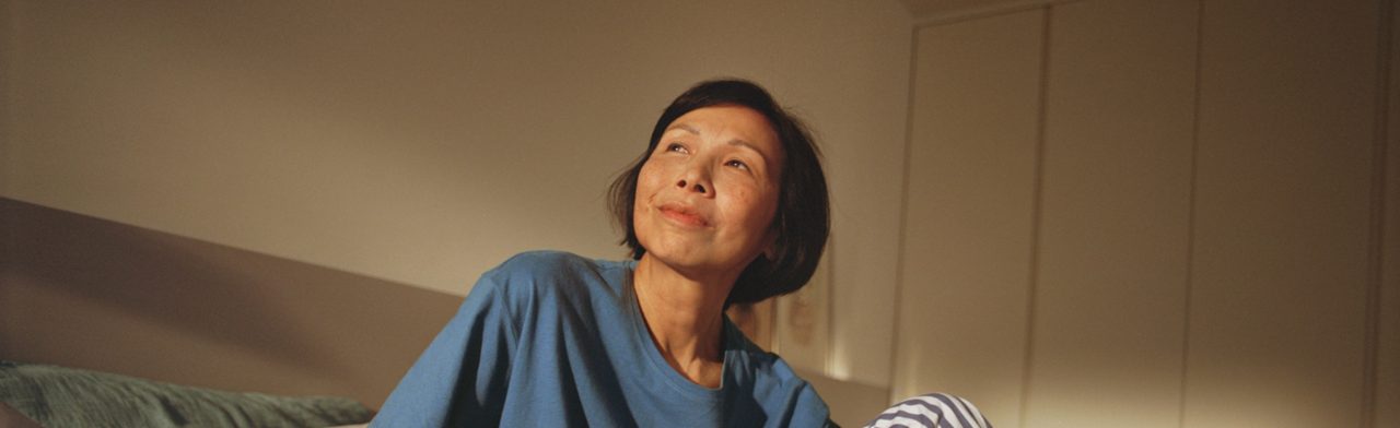 Woman in bed looking up and smiling