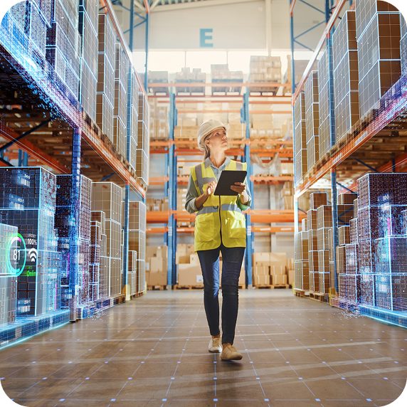 Woman walking down an aisle, in a distribution center, holding a clipboard