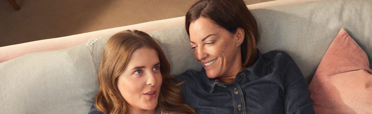 Mère et fille souriant et discutant sur le canapé