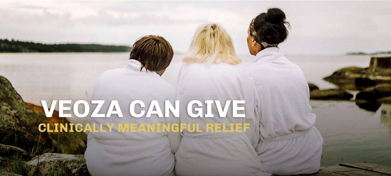 3 women in bathrobs are sitting on the beach looking out over the sea. VEOZA™ (fezolinetant) can give clinical meaningful relief 