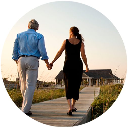 A woman and a man walks hand in hand near by the beach