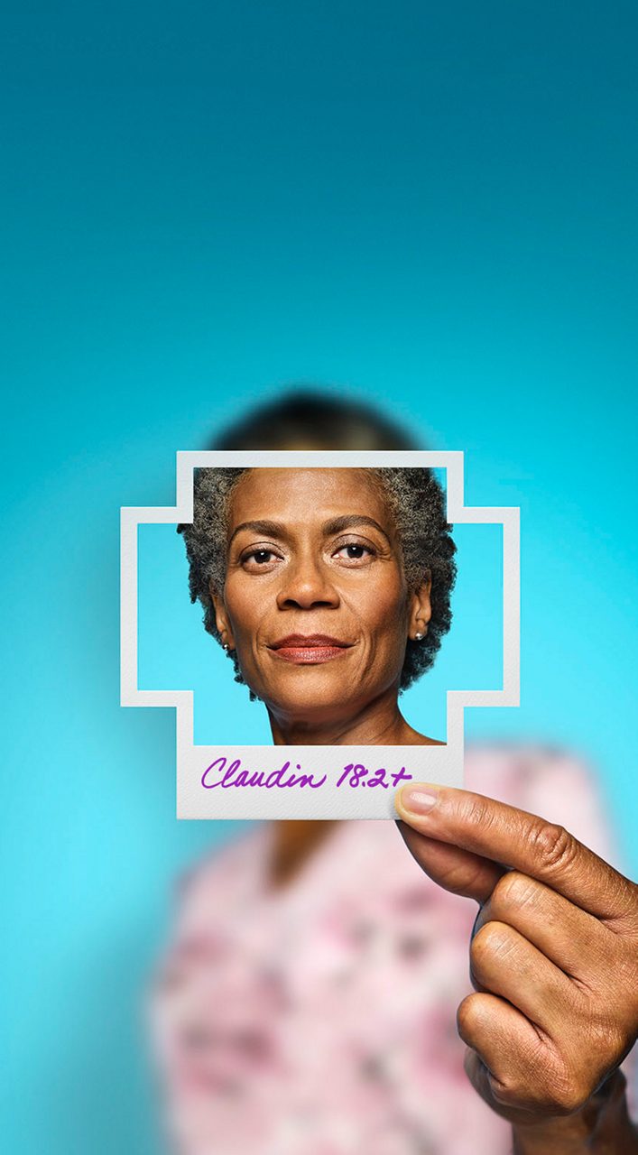 Woman in pink shirt holding up a Claudin 18.2-positive frame.