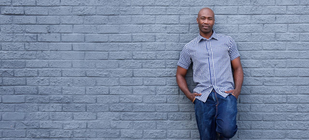 Full length portrait of a relaxed african american man leaning against wall