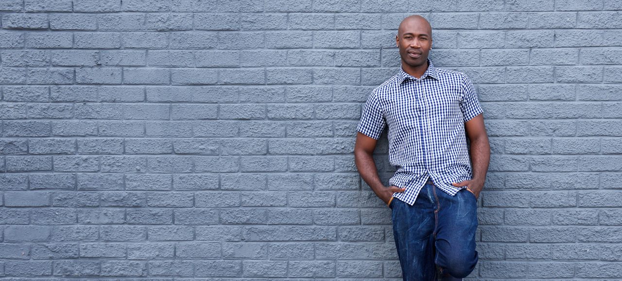 Full length portrait of a relaxed african american man leaning against wall