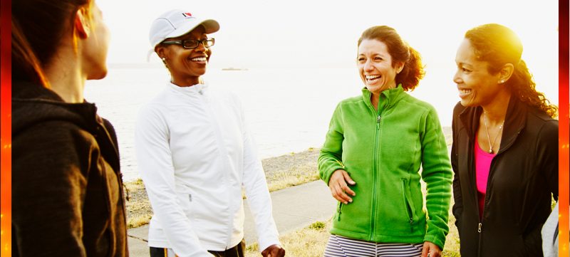 Vier sportliche Frauen lachen in der  Nähe einer Küstenlinie