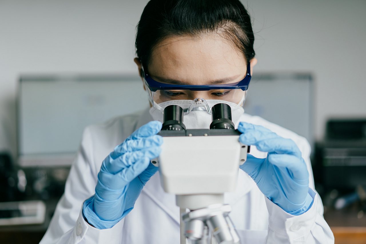 A scientist studies samples under a microscope, advancing Astellas' R&D for innovative, patient-centered therapies.