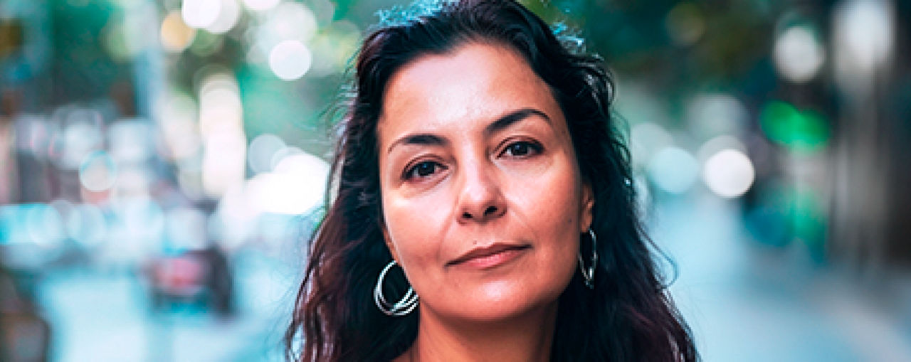 Una mujer con menopausia posa apoyada en la puerta su coche feliz tras contar su experiencia con los síntomas (SVM) 