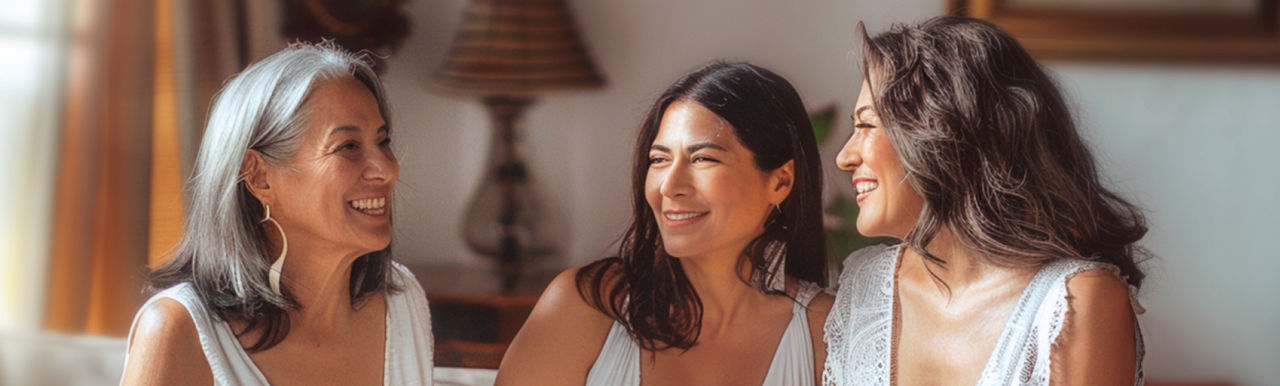 Tres mujeres con menopausia conversan y se ríen contando sus experiencias
