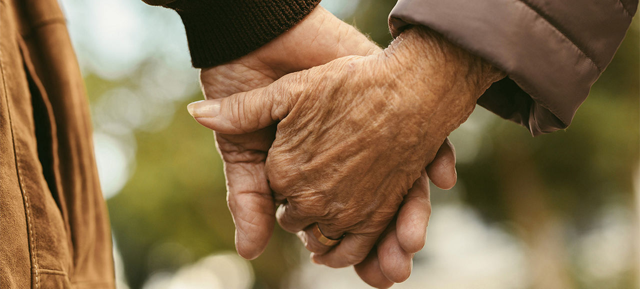 Gros plan d'un couple de personnes âgées se tenant la main et marchant à l'extérieur. Vue arrière d'un homme et d'une femme se tenant la main en marchant à l'extérieur.