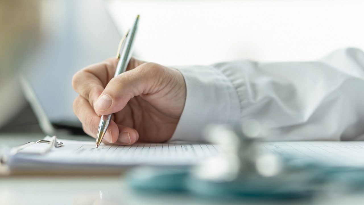 Arts schrijft op het ontslagformulier voor de persoonlijke gezondheidszorg van de patiënt, of receptpapier in het ziekenhuiskantoor, kliniekcentrum voor gezondheidszorg en levensverzekeringsconcept