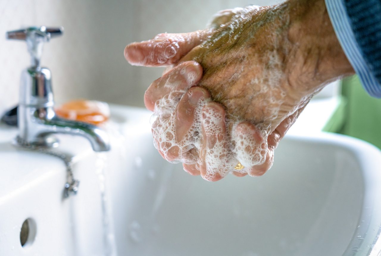 Close-up as a man washes his hands in a bathroom basin.