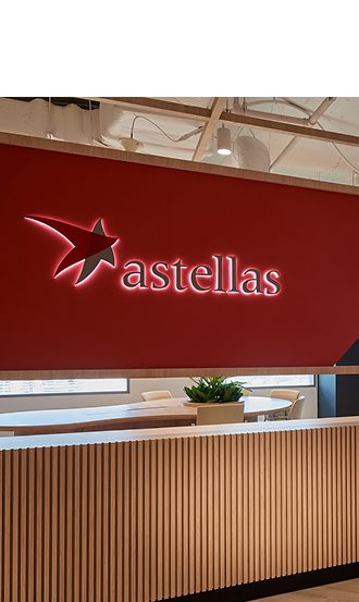 The Astellas logo displayed in a corporate office lobby, reflecting 20 years of innovation in pharmaceutical R&D and patient-centered therapies.