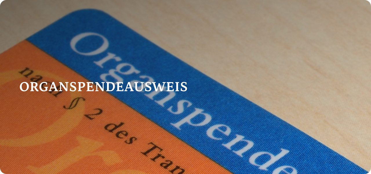 Eine Nahaufnahme eines deutschen Organspendeausweises auf einer hellen Holzoberfläche.