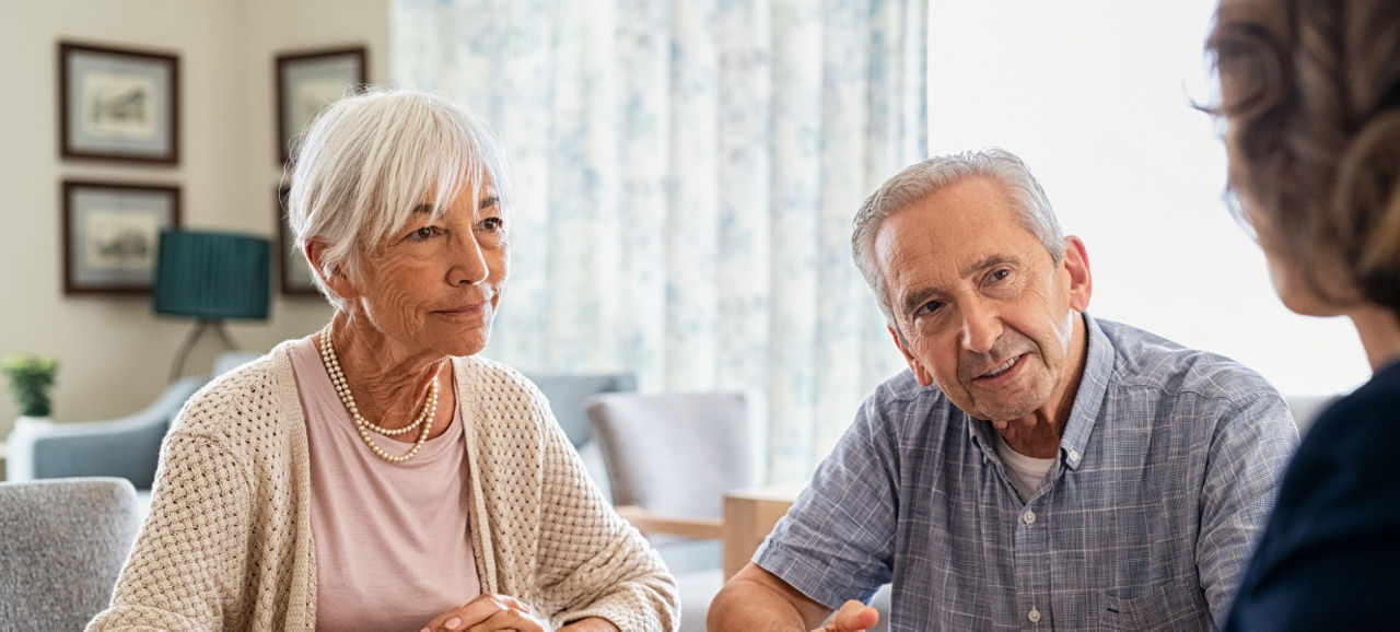 Group Of Smiling Senior Friends Walking Arm In Arm Along Shoreline Of Winter Beach
