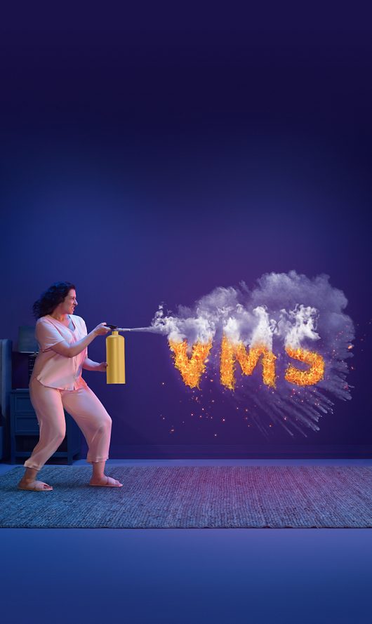 Woman spraying VEOZAH™ (fezolinetant) logo fire extinguisher at VMS fire in bedroom