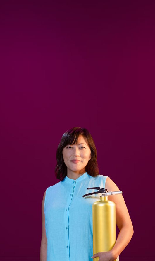 Woman in blue holding VEOZAH™ (fezolinetant) logo fire extinguisher