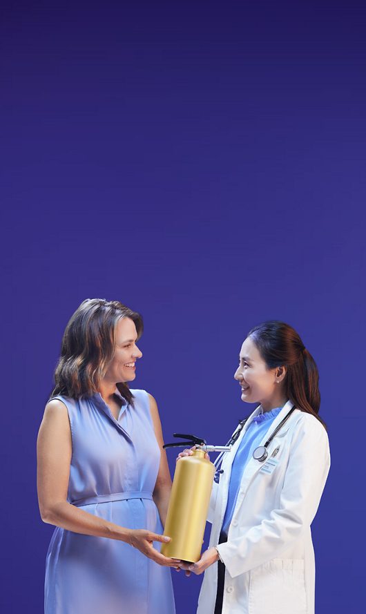 Woman and doctor holding VEOZAH™ (fezolinetant) logo fire extinguisher