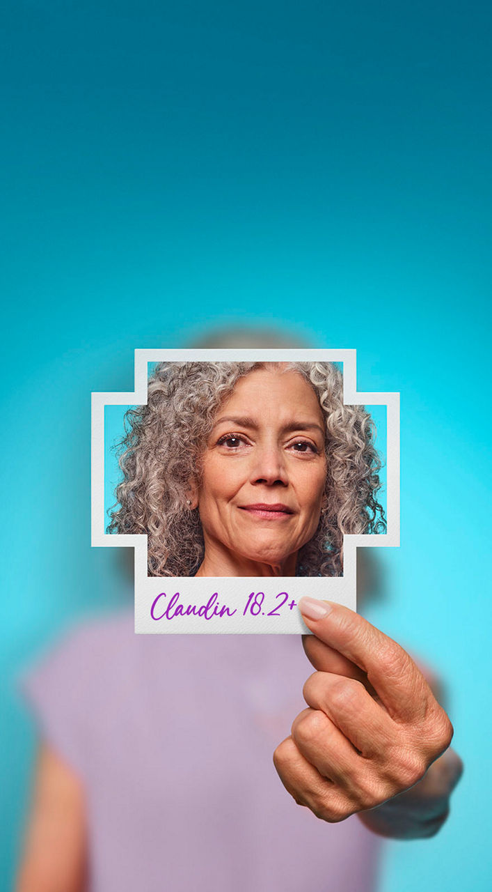 Woman holding photo of herself with Claudin 18.2+ written on it