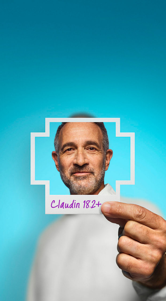 Man in white shirt holding up Claudin 18.2-positive frame