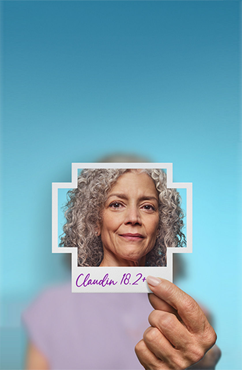 Woman holding photo of herself with Claudin 18.2+ written on it