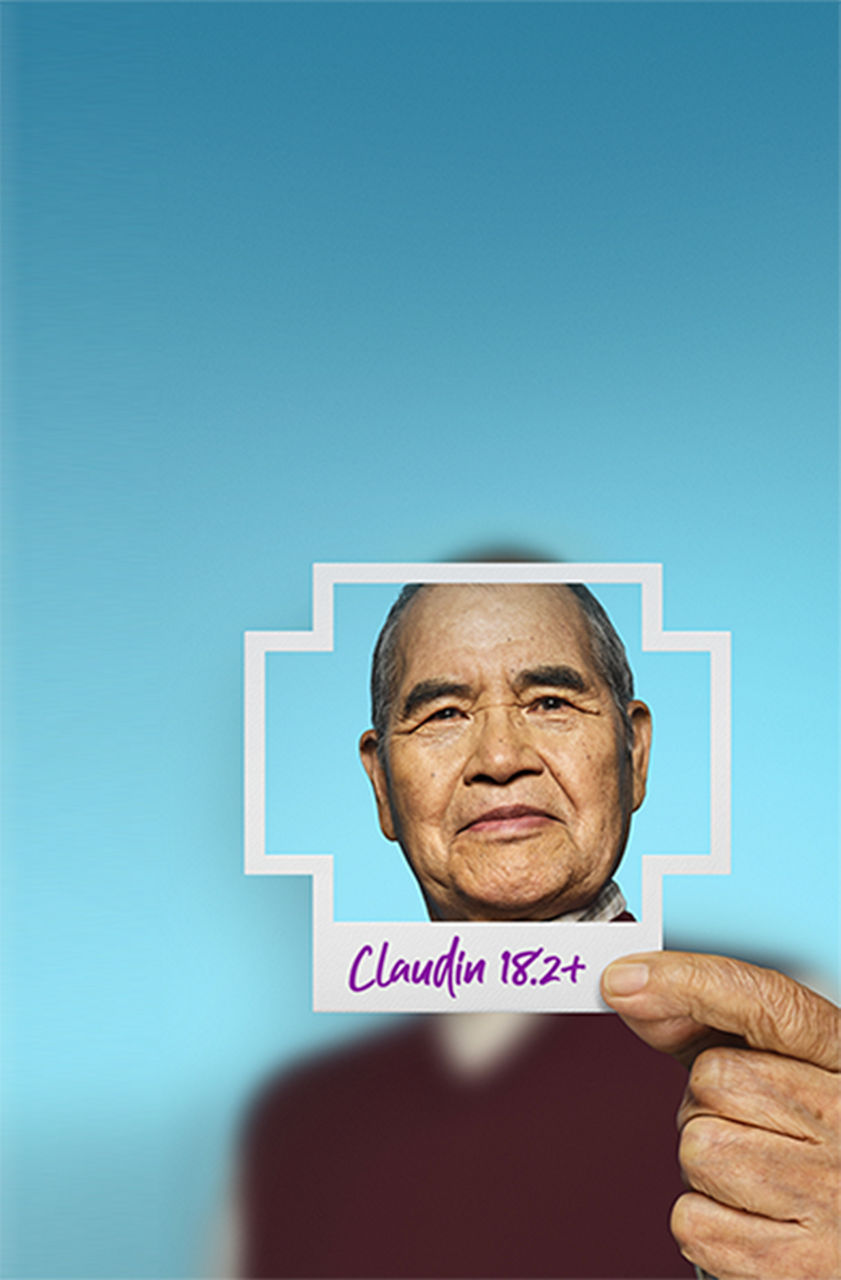 Man holding a plus-sign–shaped photo of himself with Claudin 18.2 written on the border