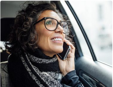 Eine Frau sitz im Auto und lacht beim Telefonieren