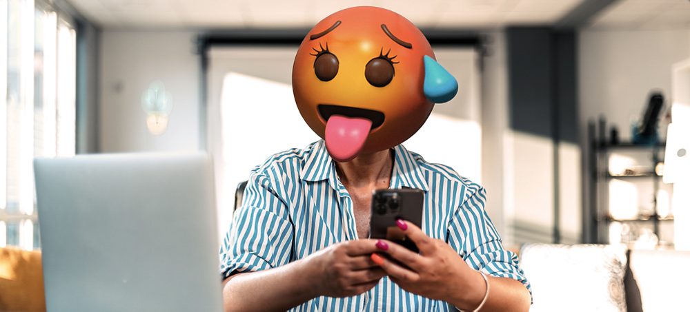 Nainen, jolla on emojipää ja puhelin