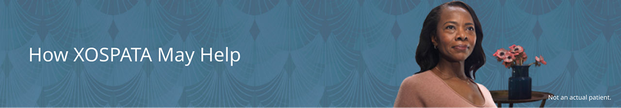 Woman smiling with flowers behind her.